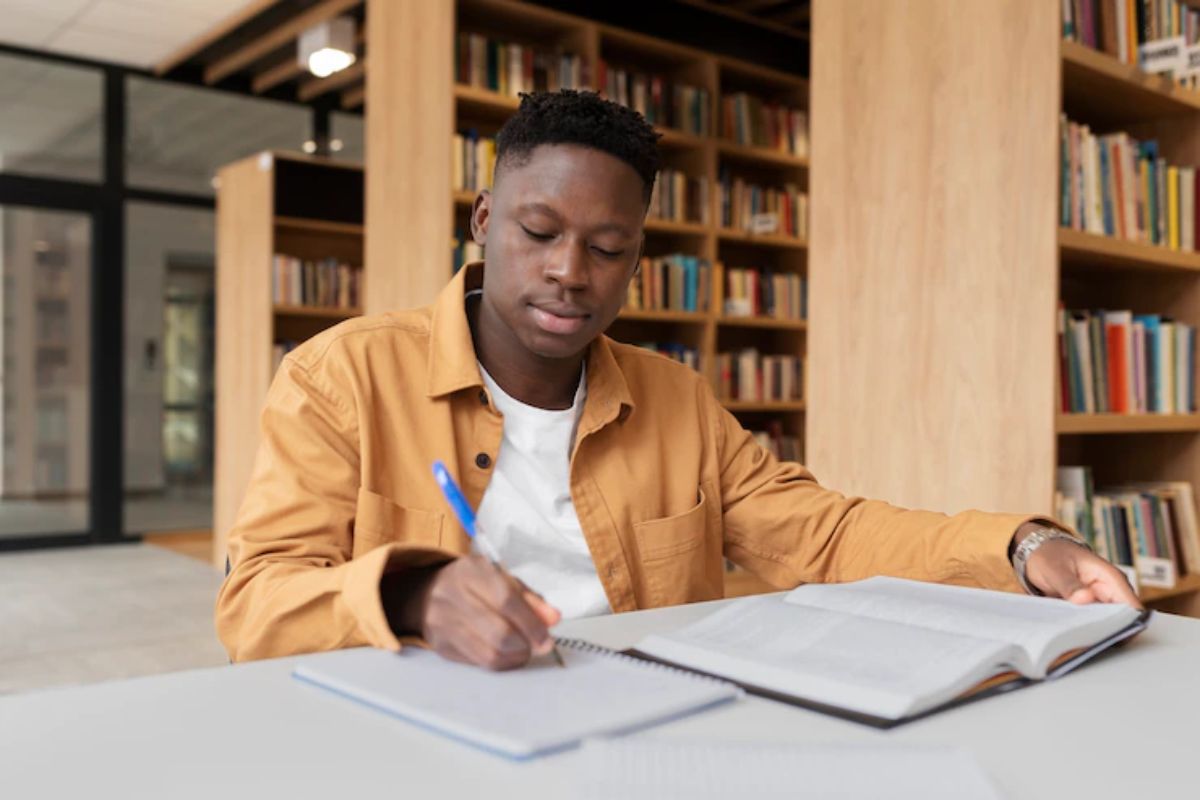 Concurso CAMPREV SP: a imagem mostra um homem jovem em uma biblioteca estudando. 