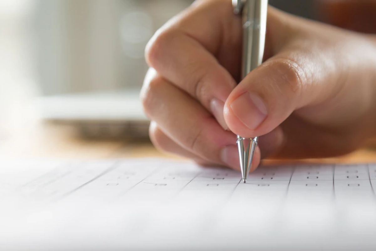Concurso de Candiota - RS: A imagem mostra uma pessoa escrevendo em uma folha de papel